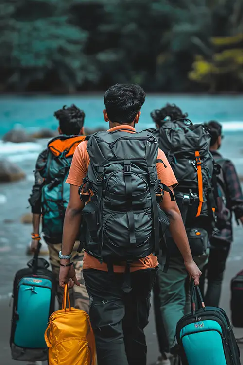Four backpackers walking near a river, leading with a man in an orange shirt