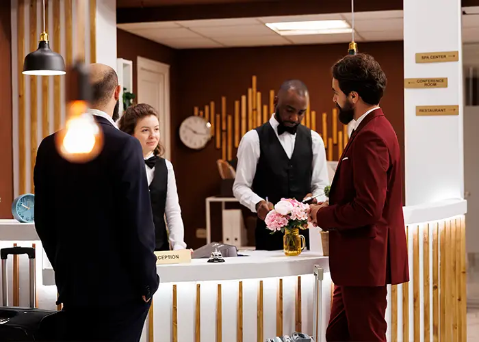 a traveler in a red suit checking in at a hotel reception with staff and modern decor asking about hotel booking.