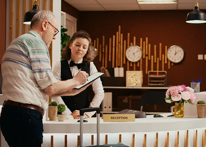 Customer signing a document at a hotel reception with decorative clocks on the wall