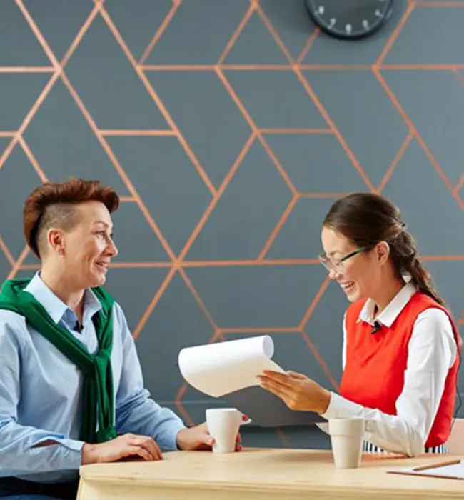 Two individuals at a table with a  travel agent holding papers in an office setting.