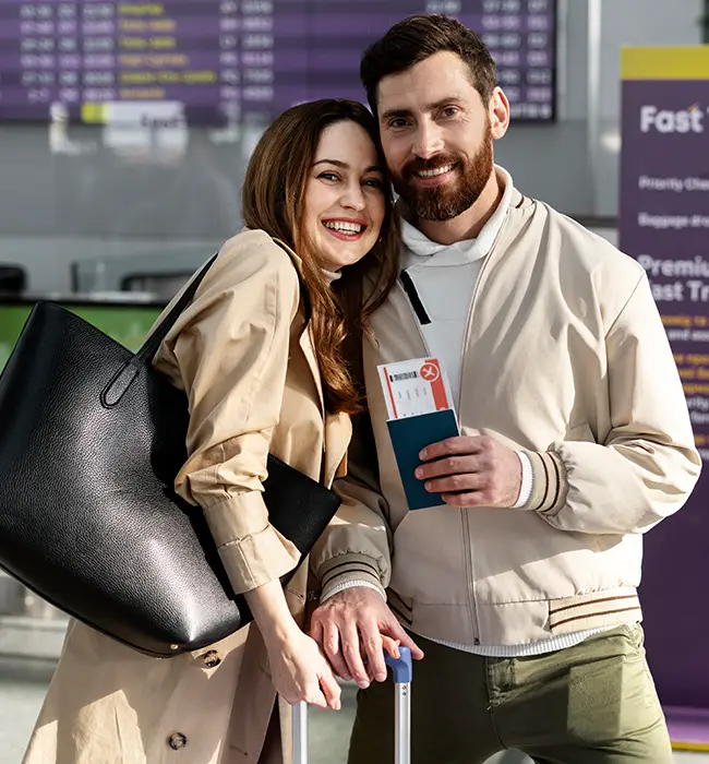 Two travelers at the airport holding tickets from travel agency and luggage, standing close together.