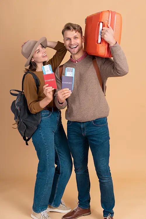 Two persons holding passports and an orange suitcase, ready to travel.