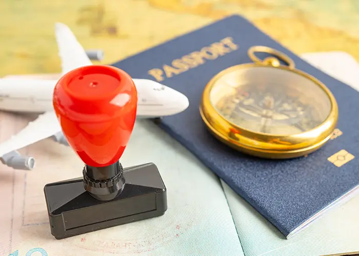 Passport with a red seal stamp, airplane model and a compass on a map.