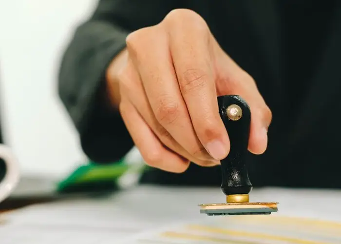 hand held stamp being pressed against visa stamoing paper